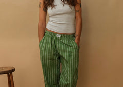 Woman wearing green and white striped lounge pants with elastic waist, paired with grey tank top