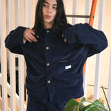 Woman wearing the Speltham navy corduroy jacket buttoned up, with matching navy corduroy trousers, in a bright room