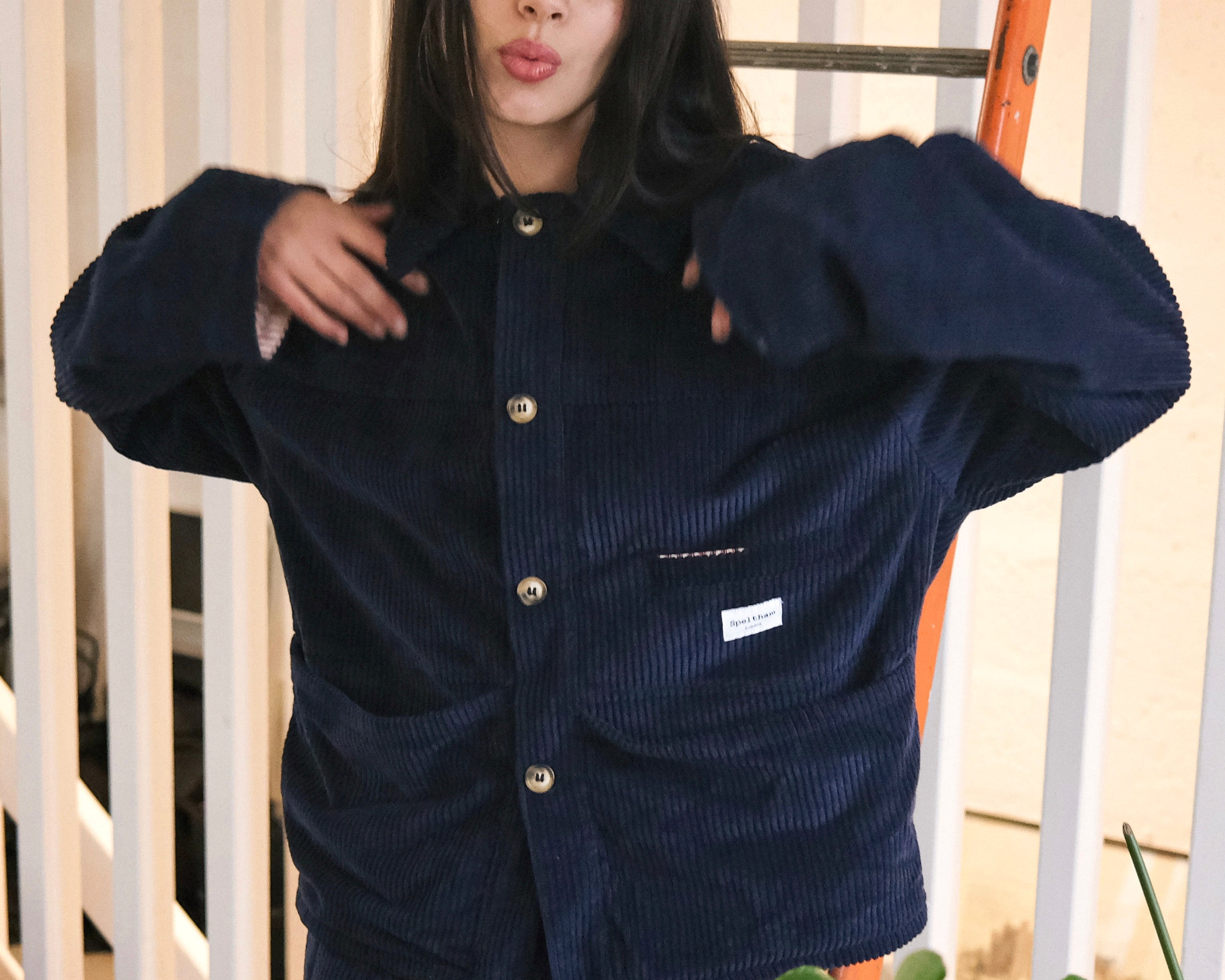 Woman wearing the Speltham navy corduroy jacket buttoned up, with matching navy corduroy trousers, in a bright room