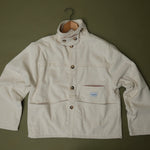 Speltham cream corduroy jacket on a hanger against a sage green wall, showing the button front and patch pockets