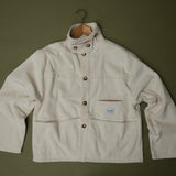 Speltham cream corduroy jacket on a hanger against a sage green wall, showing the button front and patch pockets