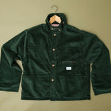 Speltham green corduroy jacket on a hanger against a sage green wall, showing the button front and patch pockets