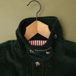Close-up of the green corduroy jacket collar on a wooden hanger, showing the wide wale cord and striped lining