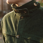 Close-up of the green corduroy jacket's high collar and horn-style button, worn outdoors