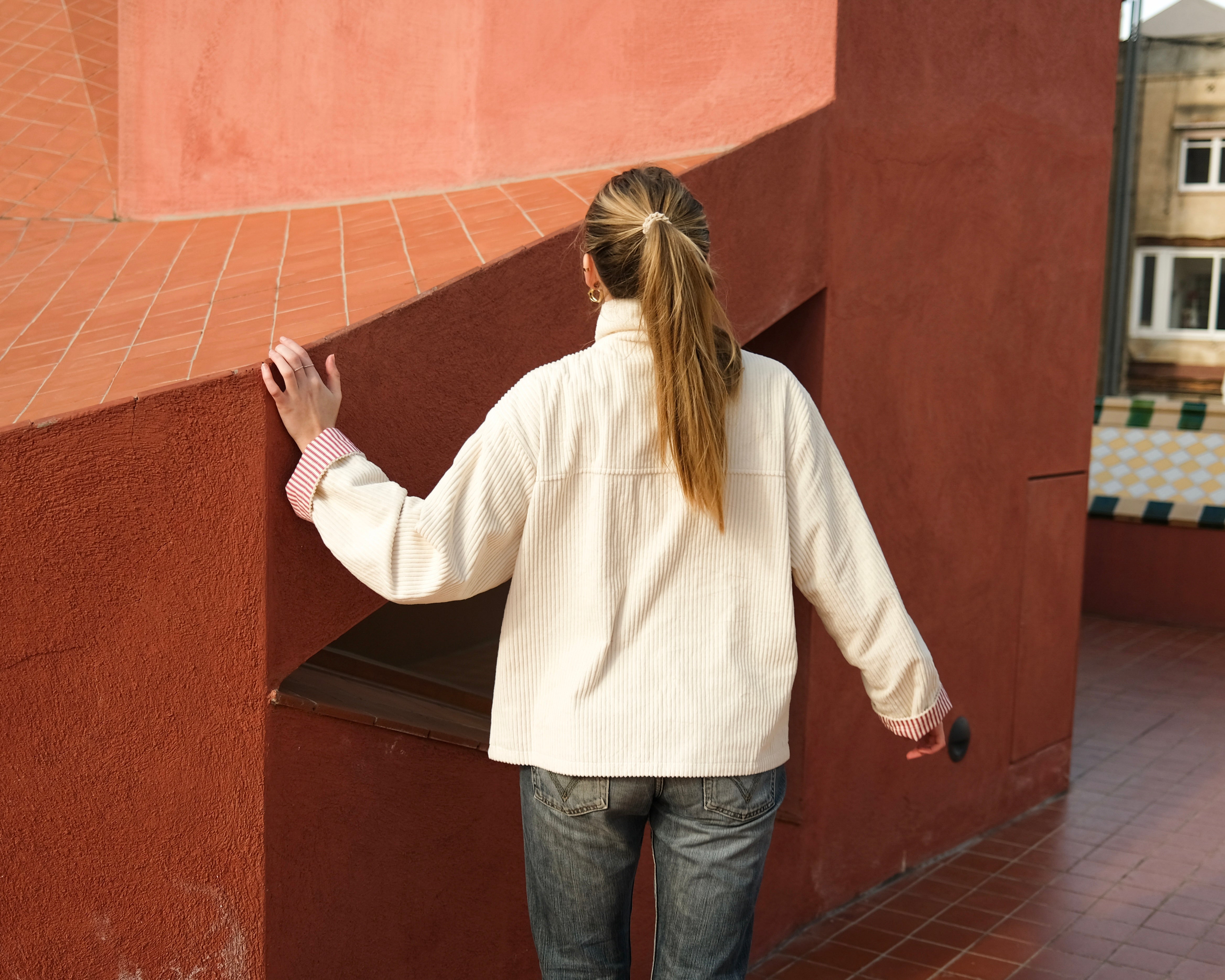Back view of the cream corduroy jacket worn with jeans, showing the relaxed fit and length