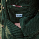 Close-up of the green corduroy jacket's front pocket and Speltham label, with the striped lining peeking out