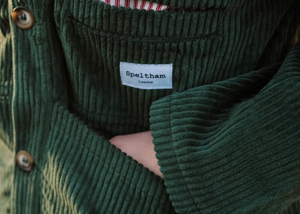 Close-up of the green corduroy jacket's front pocket and Speltham label, with the striped lining peeking out